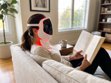Reading on the sofa while wearing the Moranoir LED light therapy mask with the neck panel attached
